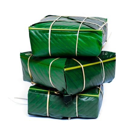 Three Chung Cakes isolated on white. Square glutinous sticky rice cake, stuffed with pork meat, green beans, wrapped tied in bamboo leaf and strings. Traditional Vietnamese New Year Tet foodの写真素材