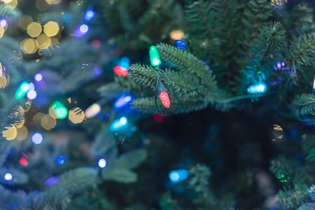Artificial Christmas tree with pre-lit multi color lights at home improvement store in Texas, America. Close-up on pine needle with nice bokeh defocused background.の写真素材