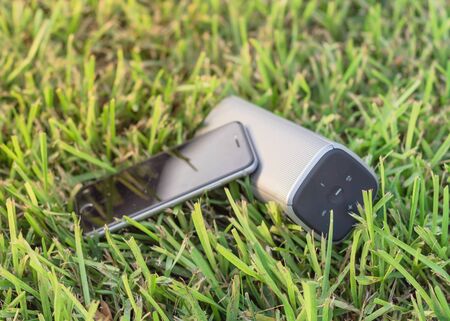 Smart phone and wireless speaker on grass lawn outdoor at sunset.の写真素材