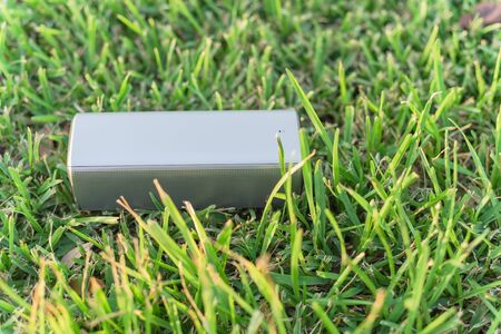 Typical wireless speaker on grass lawn at sunset.の写真素材