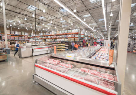Meat department and sample stand at Costco large aisle of cooler full of pork, beef, seafood