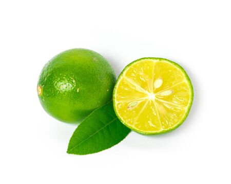 One whole raw lime with slice cutout and green leaves isolated on white background. Fresh picked Asian lemon with clipping path and copy space.の写真素材