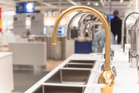 Selective focus on brand new kitchen faucet with blurry customer shopping in background at furniture retail store showroom in Texas, America.の写真素材