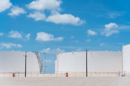 White oil storage tank with stairs under cloud blue sky in Corpus Christi, Texas, America. Large industrial container for petrol, oil, natural gas. Tank farm at petrochemical, oil refinery plantの写真素材