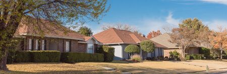 Panorama view typical bungalow style house in Dallas, Texas suburbs during fall season with colorful autumn leaves. Middle class neighborhood single story residential home with mature treeの写真素材