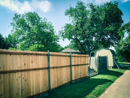 New wooden fence near collapsed slats in backyard of residential house with shed in suburban Dallasの写真素材