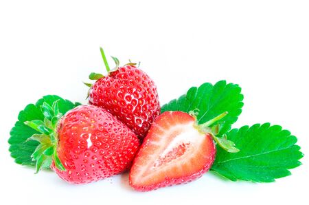 Fresh two whole strawberries with half cut and leaves isolated on a whiteの写真素材