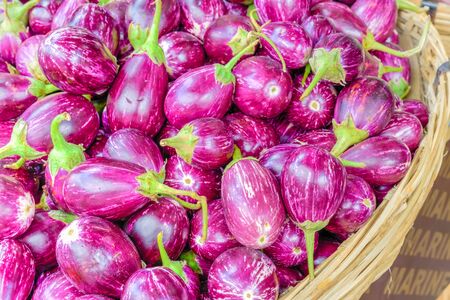 Full rattan basket of purple and oval shape Indian eggplants at street market in Little India, Singaporeの写真素材