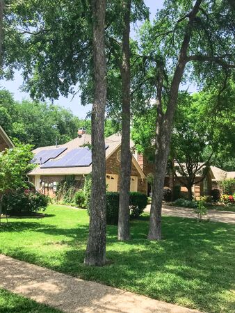 Lush green sidewalk pathway in residential area in suburban Dallas, Texas, USA and solar roof house