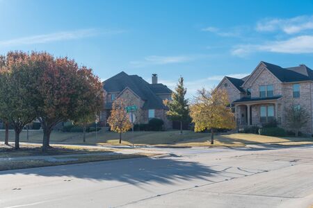 Quite new development subdivision with row of suburban houses and colorful fall foliage along sidewalk near Dallas, Texas, USAの写真素材