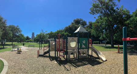 Panoramic urban playground surrounded by large trees and landmarks background in downtown Dallas,...