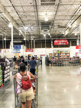 Crowded people waiting in line for checkout at Costco warehouse with social distancing near Dallas,...