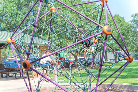 Diverse kids climbing the web net at playground near Dallas, Texas, USA close-up view