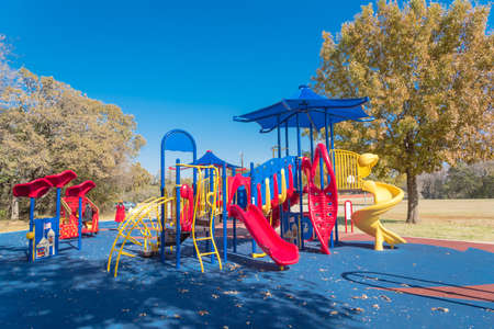 Colorful public playground near nature park with colorful fall foliage in Flower Mound, Texas, America. Kids recreation equipment with shade sail and red fire department themeの写真素材