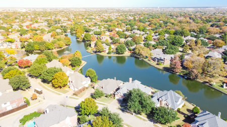 Aerial view huge suburban sprawl near Dallas, Texas, America with lakeside houses and master planned community near horizontal line in sunny autumn day with colorful fall foliageの写真素材