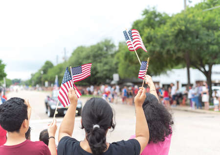Rear view diverse people waving American flags watching street parade on July 4th Independence Day celebration. United and patriotism concept.の写真素材