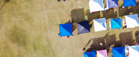 Panorama aerial view row of color tents from farmer market vendors at town square grassy lawn in...