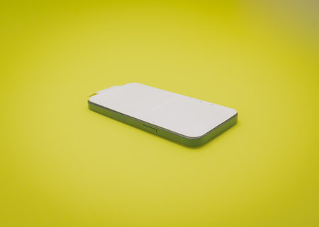 COPPELL, TX, USA-JAN 4, 2022: Brand new Apple iPhone 13 in new midnight color with white screen protector sticker isolated on yellow backgroundのeditorial素材