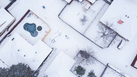 Residential house with swimming pools, playground and large backyard covered in thick snow after historic blizzard storm near Dallas, Texas, USA. Aerial suburban home back alley in snowの写真素材
