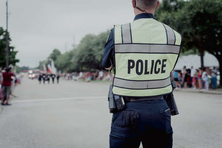 Toned photo rear view police officer at public July 4 parade event near Dallas, Texas, America. Law...