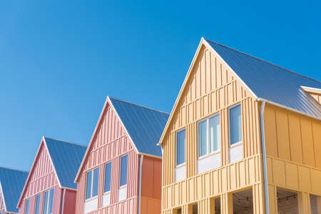 Lookup view of metal roof and gutter on row of new development colorful house with clear blue sky background.  Close-up facade of two story townhomes near Wheeler District, Oklahoma City, USAの写真素材