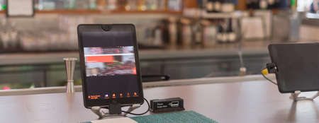 Row of tablets with swipe magnetic credit card reader to order food and drink at airport bar...