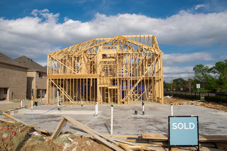 Unfinished new development wooden two-story houses with sold sign near completed homes, beam truss frame, slab foundation, utilities plumbing pipeline installation. Suburban housing Irving, Texas, USの写真素材