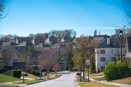 Three story, row of two-story houses along residential street leading down a steep hill in new development suburban neighborhood outside Atlanta, Georgia, USA, upscale homes. Sunny cloud blue skyの写真素材