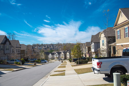 Parked cars at front garage along residential street leading down a steep hill in new development suburban neighborhood suburbs Atlanta, Georgia, USA, row of upscale homes. Sunny cloud blue skyの写真素材