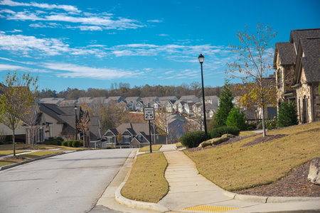 Speed limit at 25 miles on residential street leading down steep hill, row of two-story houses, new development subdivision neighborhood upscale homes, Atlanta, Georgia, USA. Sunny cloud blue skyの写真素材