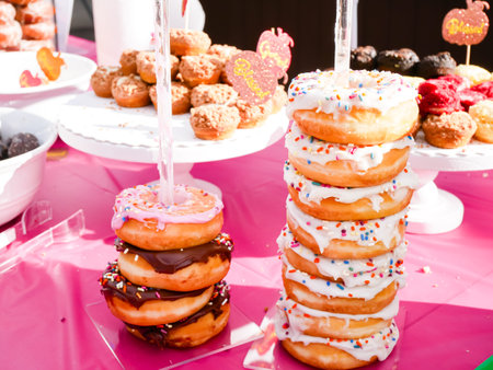 Stack of icing sprinkle, chocolate glazed donuts, cookies on outdoor party feast table at Thanksgiving event in Dallas, Texas, USA, treat sugar dessert holiday season. Doughnut collection varietyの写真素材