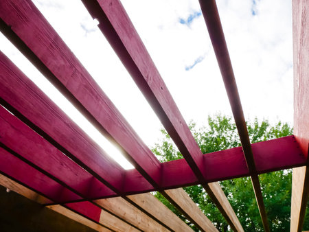 Old natural wood grain roof rafters vs new stained redwood color with large tree background, house remodel, oil latex paint compares, transition, transformation, comparison, progress concept. DYIの写真素材