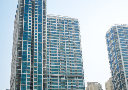 Upward view glass office building, high-rise apartment complex condominium under clear blue sky in...