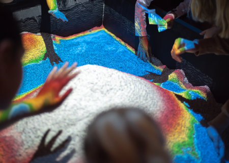 Kids hands on colorful augmented reality sandbox with overhead sensors, colored lights, exhibit on...