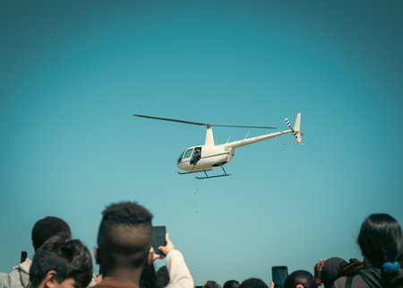 Toned photo hands taking photo hovering helicopter drops colorful eggs and goodies at Easter event...
