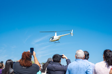 Hands taking photo hovering helicopter drops colorful eggs and goodies at Easter event in...