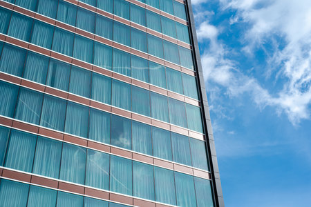 Cloud reflection on glass wall of modern high rise hotel room with blackout curtains in Texas,...