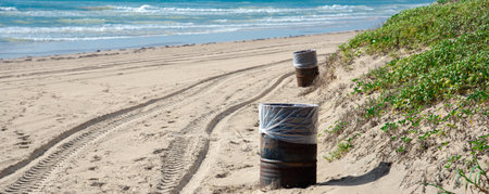 Panorama view trash can barrel white plastic liner along white sandy shoreline with ATV tracks in South Padre Island, tropical beach of Texas, sunny blue cloud sky, littering management ecology. USAの写真素材