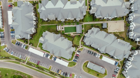 Straight aerial view new construction apartment complex with metal roofing, outdoor areas, busy...