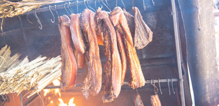 Close-up panorama dried buffalo and pork beef jerky hanging on traditional kitchen of ethnic people, Mai Chau, Hoa Binh, Vietnam, smoked spied dried barbeque iron meat hanger wooden fire cooking. Asiaの写真素材