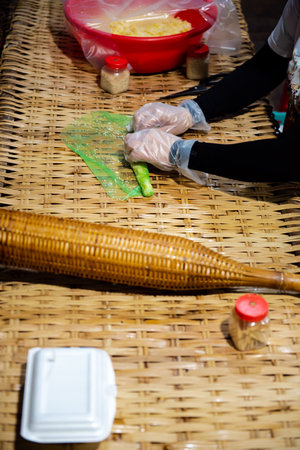 Bamboo mat with food foam container, Asian woman hands in food gloves making traditional Vietnamese...