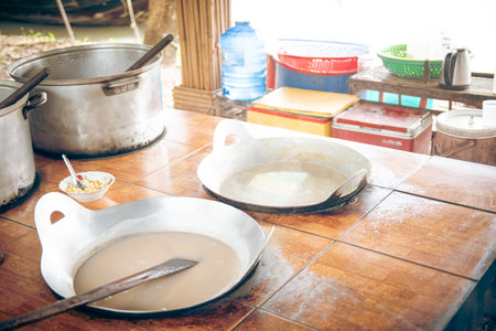 Natural ingredients squeezed coconut milk, cream, sugar and malt syrup in flat cast iron cooking pan at local handmade candy factory in Can Tho, Vietnam, glutinous rice flour in food production. Asiaの写真素材