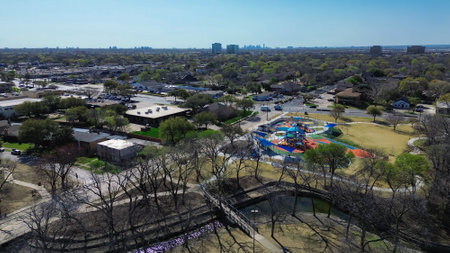 Dallas downtown skylines background from suburban park with colorful outdoor playground climbing sphere, swings, obstacle courses, sensory play area, trail, rawhide creek, Farmers Branch, Texas. USAの写真素材