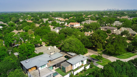 Metal and shingle roofing on large two-story suburban luxury mansion houses with downtown Dallas skylines background, lush green trees in Preston Hollow affluent neighborhood, mature landscape. USAの写真素材