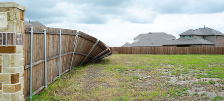 Panorama view neighborhood corner privacy brick and stone with collapsed wooden fence by strong winds damages at residential area suburban houses in Princeton, Texas, tornado insurance claims. USAの写真素材