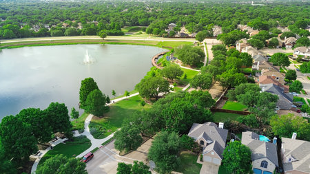 Lush green community Rheudasil Park in Flower Mound, Texas with curved boardwalk, walking trails, playground, upscale suburban two-story houses with resort-style swimming pool, grassy lawn, aerial. USの写真素材