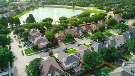 Rheudasil Park in Flower Mound, Texas, featuring pond with fountain, boardwalk, walking trails, lush green trees, playground, and surrounding suburban homes in the Dallas Fort Worth metroplex. USAの写真素材