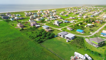 Large vacant land near raised beach house with spacious grassy backyard in Port Bolivar, Texas. Elevated sturdy stilts homes, design common along Gulf Coast for storm resilience, flood protection. USAの写真素材
