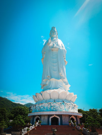 Large white Lady Buddha statue at Linh Ung Temple, Da Nang, stands tall on lotus pedestal base with...