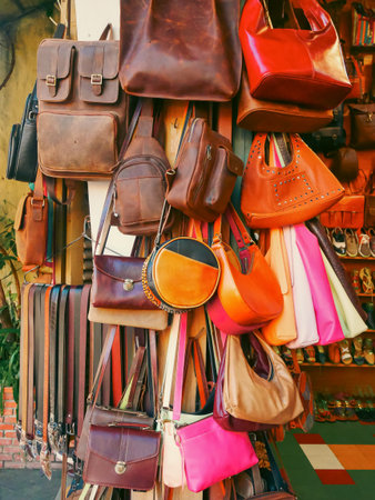 Leather bags, backpacks, shoes, sandals, and belts hang in dense, colorful street-side display in Hoi An, Danang. The outdoor setting adds authenticity and charm to handcrafted retail scene. Vietnamの写真素材